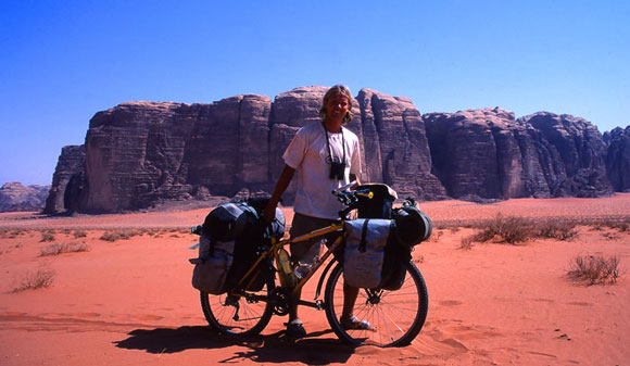 Jag släpar cykeln genom mjuk tegelröd sand i Wadi Rum.